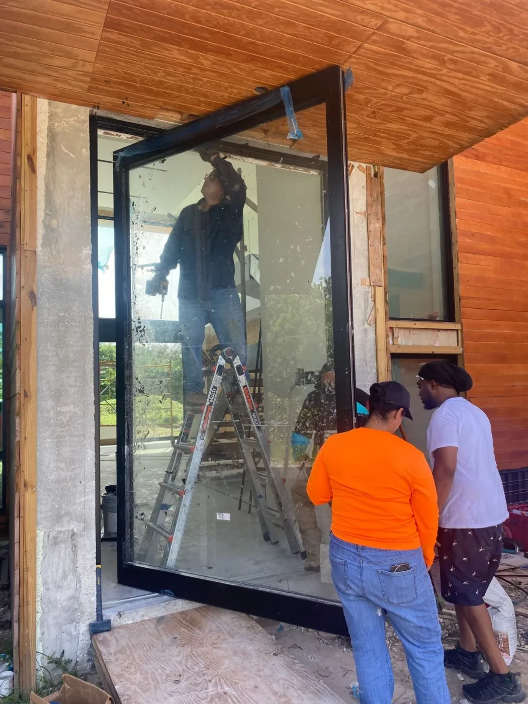 Installers setting a large impact pivot door