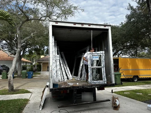 Crew unloading new ESWindows impact windows from a delivery truck